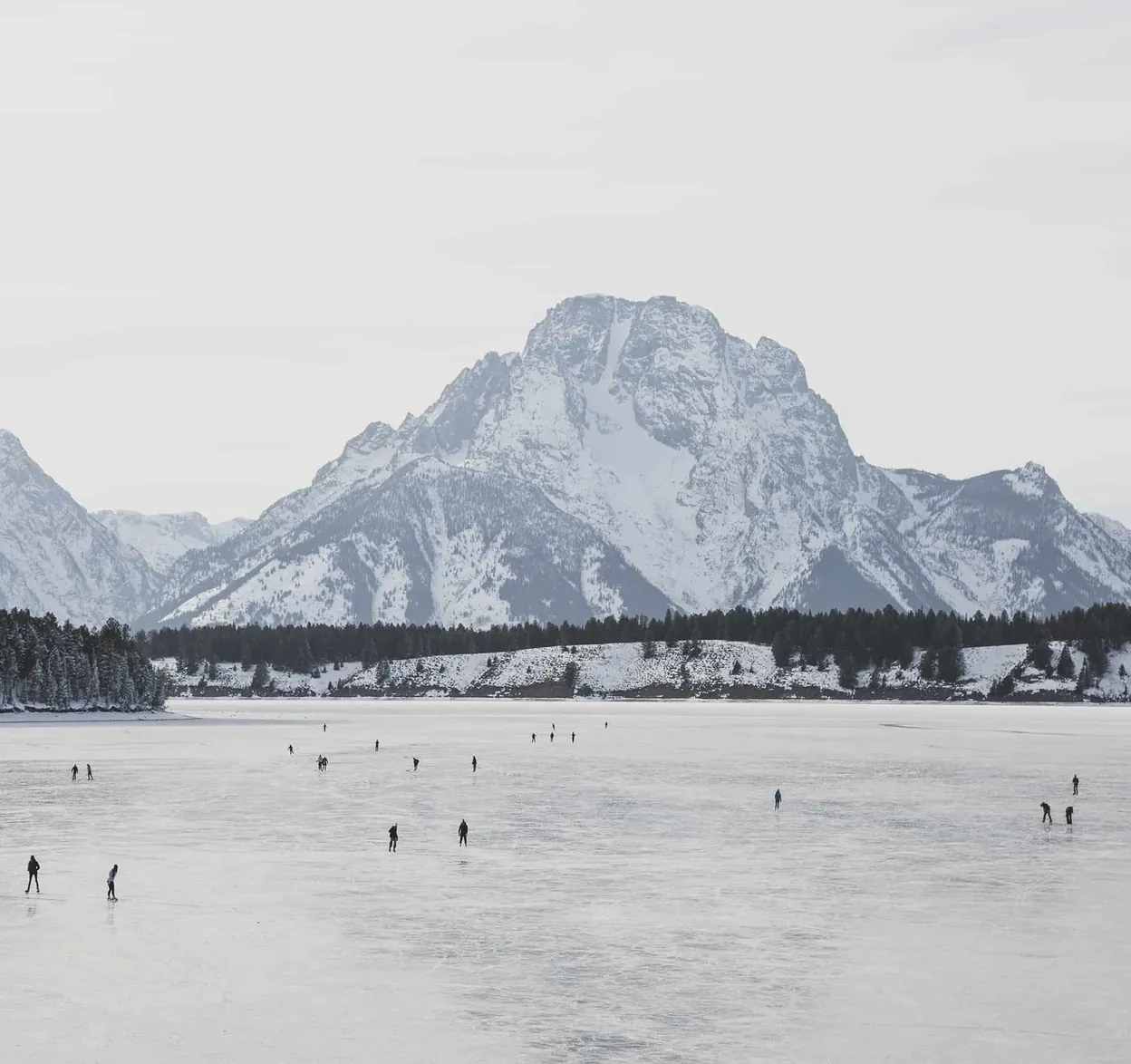 Mount Moran above a frozen lake with skaters far below